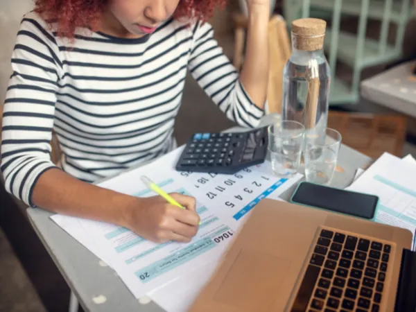 Persona emplenant la declaració de la renda amb calculadora i portàtil